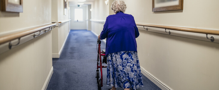 elderly woman walking down hallway with a walker nursing home abuse and neglect