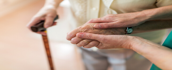 someone holding elderly womans hand who is holding a cane nursing home abuse and neglect